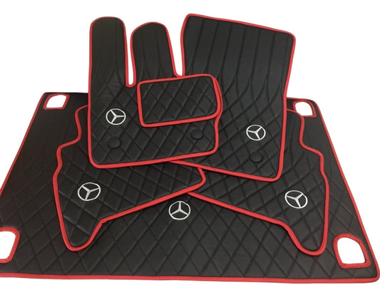 A set of black floor mats with red trim for a Mercedes-Benz G Wagon, including a logo emblem on the front mat.