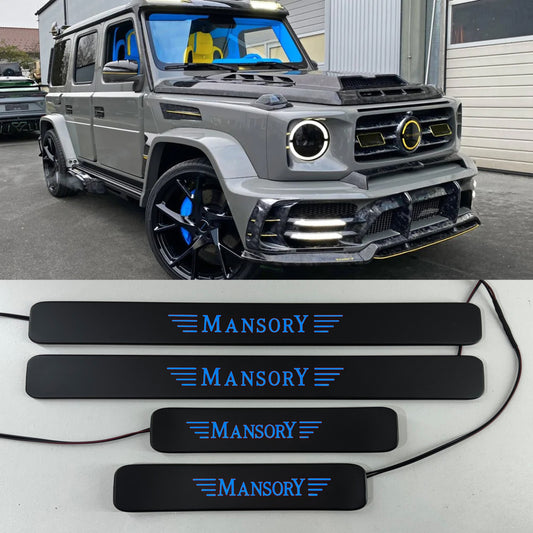 Mercedes-Benz G-Class W463A W464 door sills in matte black with LED lights, branded with 'MANSORY', displayed on a table and fitted on a vehicle.